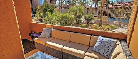 A balcony with wicker furniture and a view of a swimming pool.
