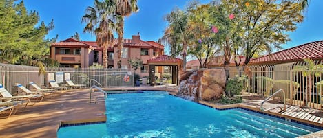 A swimming pool with lounge chairs and a house in the background.