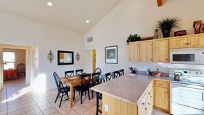 A spacious kitchen with wooden cabinets, a dining area with a table and chairs, and a microwave.