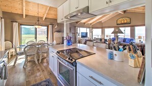 A spacious kitchen with a large island, wooden ceiling beams, and a view of the outdoors. - Spectacular Ocean View Retreat w/ Hot Tub (Manchester)