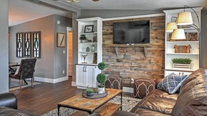 A modern living room with a fireplace, a flat-screen TV, and a ceiling fan. - Rustic Chic Home: 10 Mi to Otter Creek State Park! (Kingston)