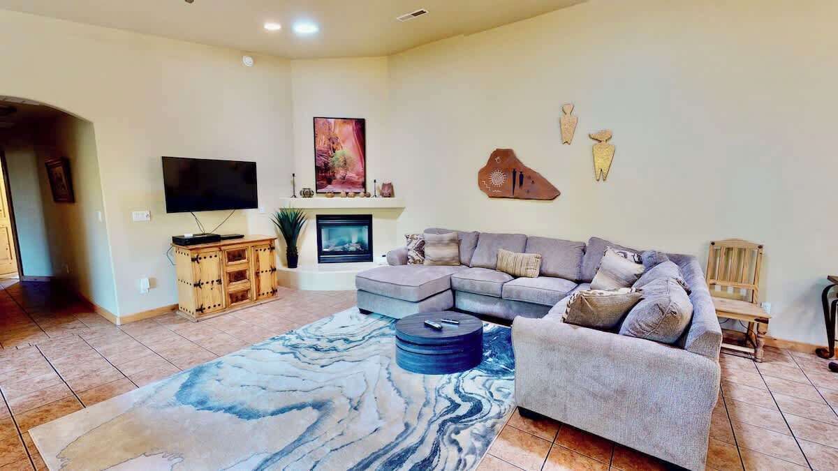 A living room with a sectional sofa, a flat-screen TV, a fireplace, and decorative wall art.