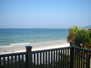 A beach view from a balcony with a railing, palm trees, and a clear sky. - 5 Bedroom Beach Front Home with Screened in Deck (Cape San Blas)