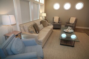 A living room with a sofa, two armchairs, a glass coffee table, and a lamp. - 5 Bedroom Beach Front Home with Screened in Deck (Cape San Blas)