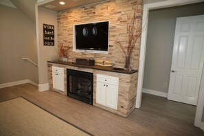 A modern kitchen with a stone backsplash, a flat-screen TV, and a fireplace. - 5 Bedroom Beach Front Home with Screened in Deck (Cape San Blas)