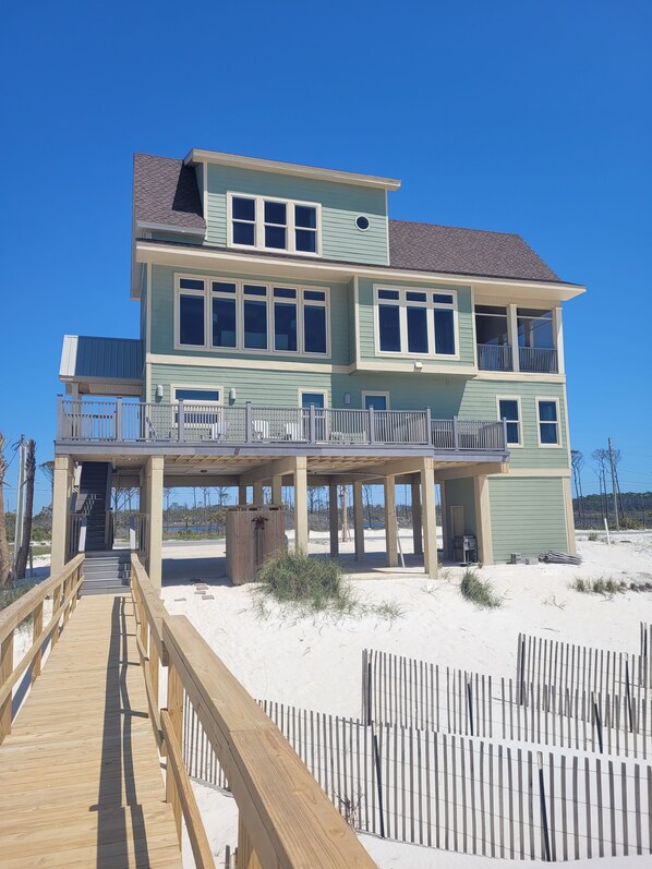 A two-story beachfront house with a wooden deck and a covered walkway. - 5 Bedroom Beach Front Home with Screened in Deck (Cape San Blas)