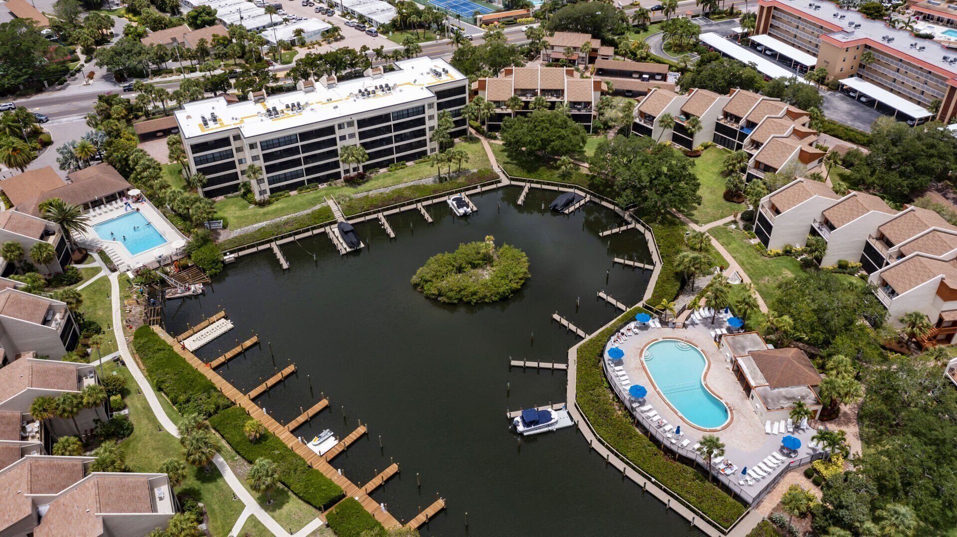 An aerial view of a resort with a central water body, docks, and a pool area.