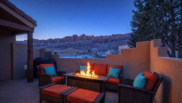 Une terrasse extérieure aménagée avec des meubles en osier, un foyer et une vue sur un paysage montagneux.