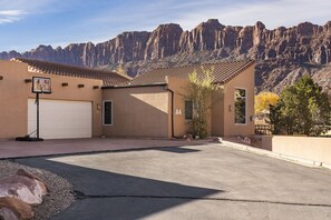 A residential building with a garage, a basketball hoop, and a view of a mountain range. - Moab Basecamp! 10 min to Arches | Pool & Hot tub (Moab)