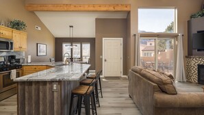 Une cuisine moderne dotée d’un grand îlot central, de meubles en bois et d’un coin repas avec un canapé et des chaises.