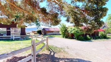 A rural property with a gravel driveway, wooden fences, and multiple buildings with red roofs.