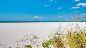Una playa con arena blanca y cielo azul claro.