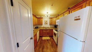 A kitchen with wooden cabinets, a refrigerator, a microwave, and a stove. - Red Cliffs Condos - 1H, Enjoy Moab Rim Views While (Moab)