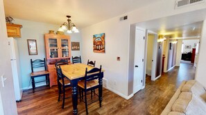 Uma área de refeições com uma mesa e cadeiras de madeira, um armário com portas de vidro e um quadro na parede.