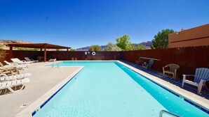 A rectangular swimming pool with a wooden deck and lounge chairs on one side. - Castle View - 3368, 3 Bed 2 Bath Town Home On Moab (Moab)
