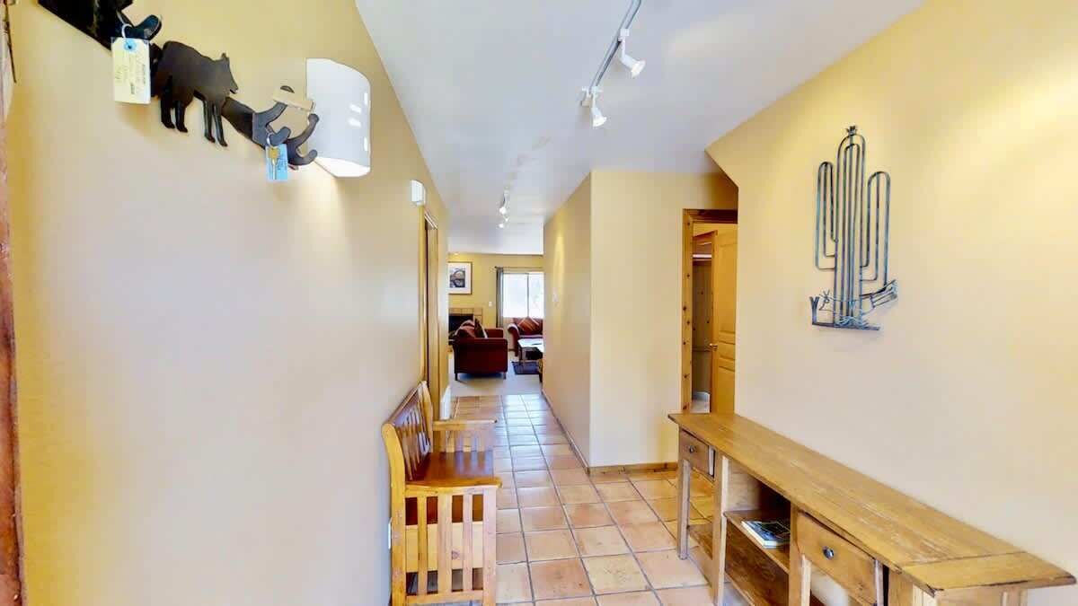 Un couloir avec un banc en bois, une table en bois et une décoration murale représentant un cactus.
