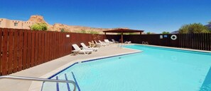 A swimming pool with a wooden fence, lounge chairs, and a pergola. - Castle View - 3368, 3 Bed 2 Bath Town Home On Moab (Moab)