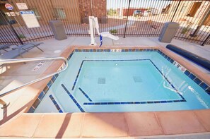 A swimming pool with a tiled edge, a safety ladder, and a fence. - Red Cliffs Condos - 1B, Dramatic Moab Rim Views, L (Moab)