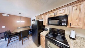 A kitchen with a dining table, chairs, a refrigerator, a microwave, and an oven.