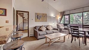 Ein geräumiger Wohnbereich mit Sofa, Couchtisch und Esstisch. Eine Treppe führt in eine obere Ebene.