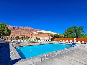 A swimming pool with lounge chairs and a mountain backdrop.