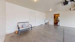 Una habitación amplia con un banco, una pared blanca y una puerta.