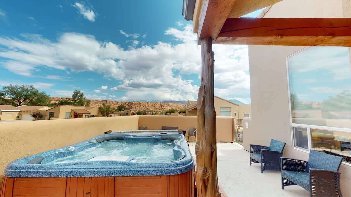 Een hottub met een houten omlijsting, buitenmeubilair en uitzicht op een woestijnlandschap.