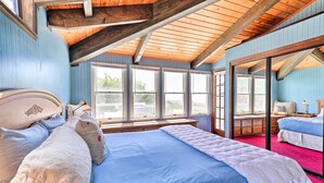 Une chambre avec un grand lit, un plafond en bois et une vue sur l’extérieur, visible à travers une porte vitrée.