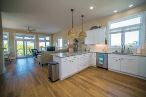 A spacious kitchen with white cabinets, a granite countertop, and a large window.