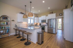 A modern kitchen with white cabinets, stainless steel appliances, and a central island with bar stools.