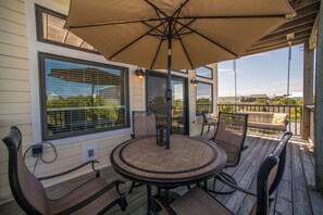 Une terrasse couverte avec une table ronde et des chaises, un parasol suspendu et une vue sur les environs.