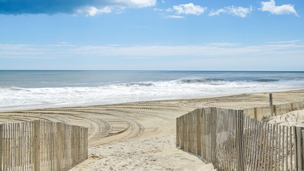 Ein Strand mit Holzzäunen und blauem Himmel.