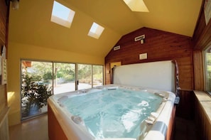 Un jacuzzi en una habitación con paredes de madera y ventanas amplias.