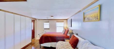 Une chambre à coucher avec un lit, un canapé, un tableau et une fenêtre.