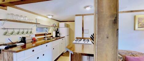 A kitchen with white cabinets, a wooden countertop, and a gas stove.