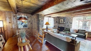 Um interior rústico com lareira de pedra, mobiliário de madeira e um espaço de refeições.