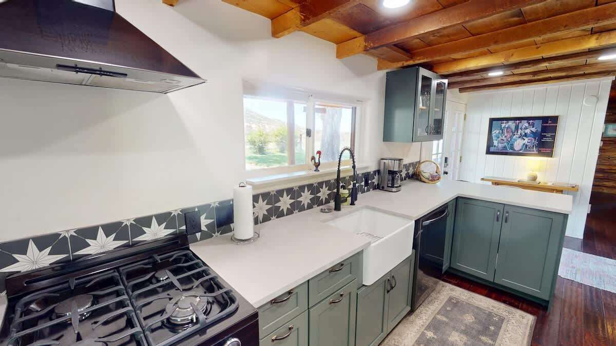 A kitchen with a stove, sink, and cabinets.