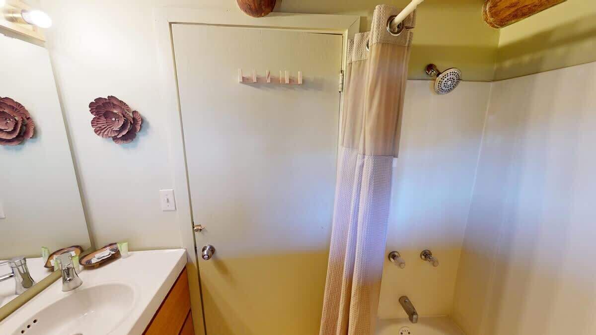 A bathroom with a shower, a sink, and a mirror.