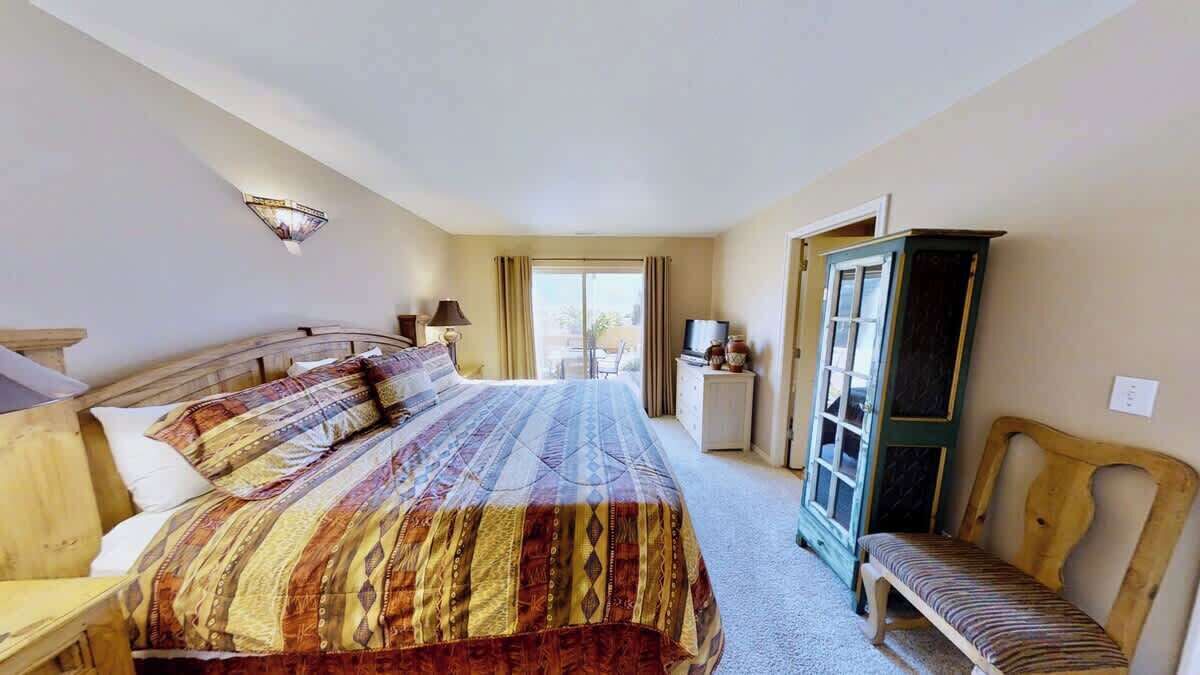 A hotel room with a large bed, a wooden bench, a television, and a cabinet.