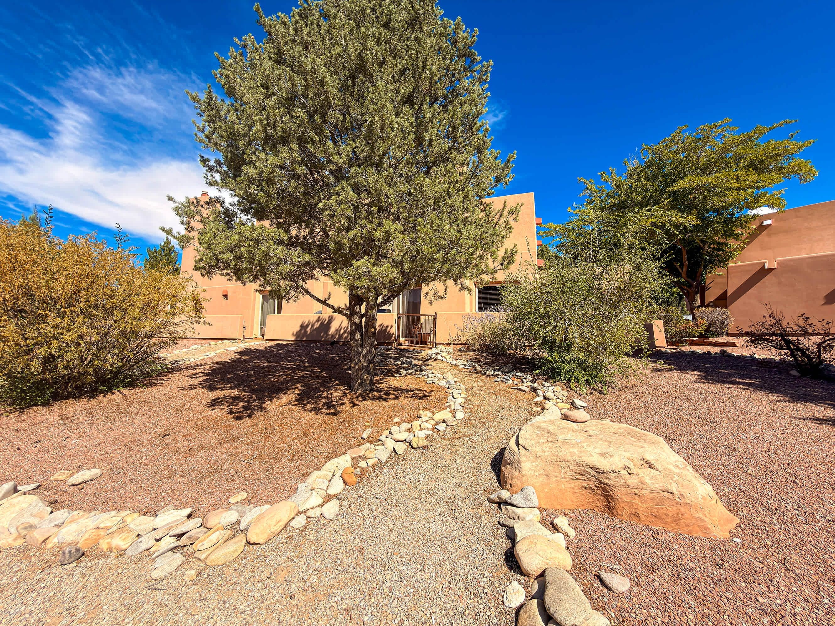 A building with a stone pathway leading to the entrance, surrounded by desert vegetation and a clear blue sky.
