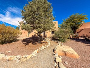 A building with a stone pathway leading to the entrance, surrounded by desert vegetation and a clear blue sky. - Sunset View - 3234 (Moab)