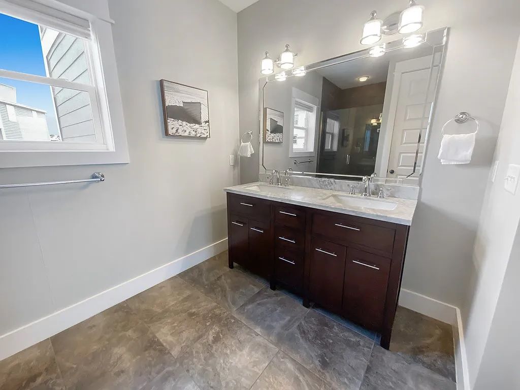 A bathroom with a double vanity, a large mirror, and a towel rack.