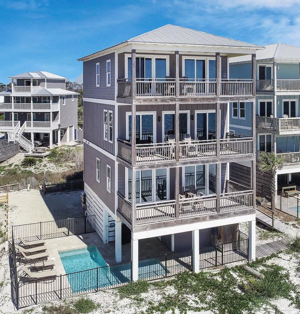 A multi-story beachfront building with balconies, a swimming pool, and a beach access area.