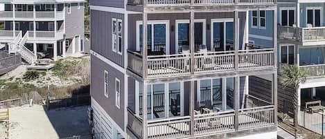 A multi-story beachfront building with balconies, a swimming pool, and a beach access area.