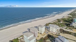 A coastal view with beachfront properties, including multi-story buildings and a beach.