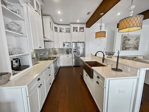 A modern kitchen with white cabinetry, a central island, stainless steel appliances, and pendant lighting.