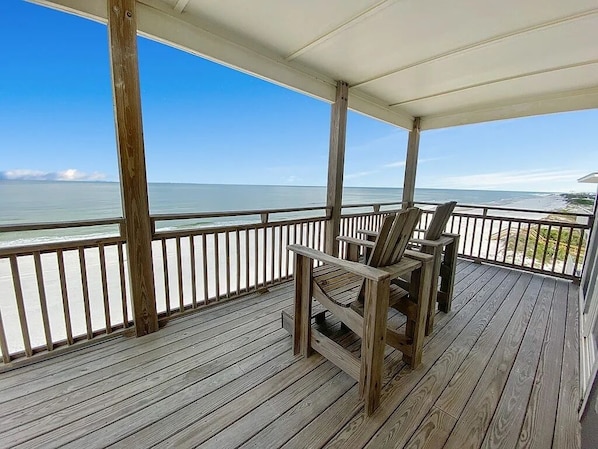 A wooden deck with a railing overlooking a beach.