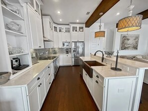 A modern kitchen with white cabinetry, a central island, stainless steel appliances, and pendant lighting.