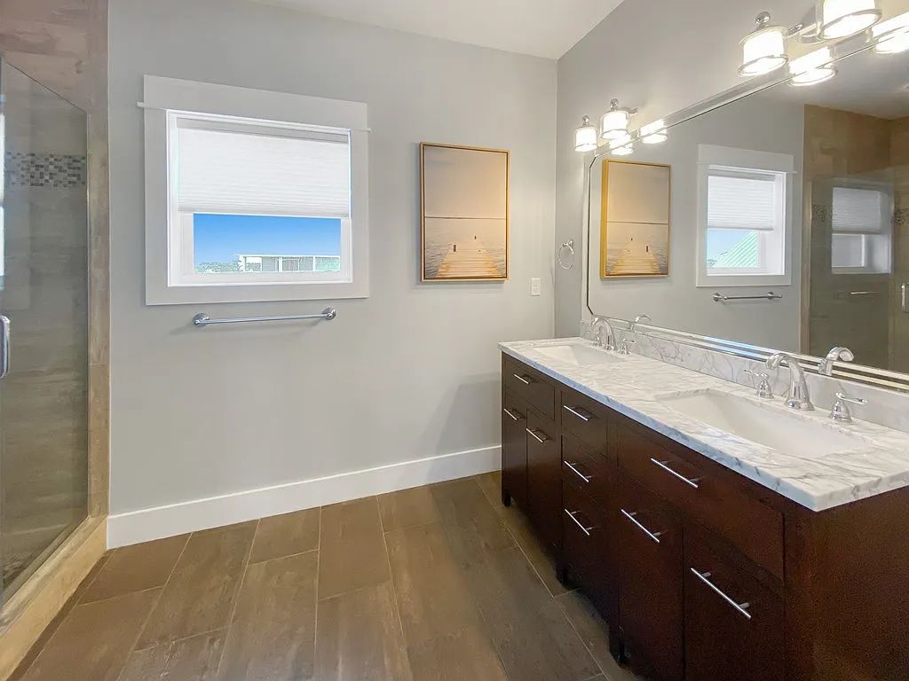 A bathroom with a large mirror, two sinks, and a shower.