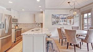 A modern kitchen with stainless steel appliances, a marble island, and a dining area with a chandelier. - Perfect Passage To Copper Mountain with available hot tub! PP327 (Copper Mountain)